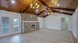 unfurnished living room with an inviting chandelier, tile patterned flooring, wood ceiling, and vaulted ceiling with beams