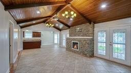 unfurnished living room featuring a stone fireplace, wood ceiling, french doors, and vaulted ceiling with beams