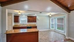 kitchen featuring kitchen peninsula, vaulted ceiling with beams, wooden ceiling, and light tile patterned floors