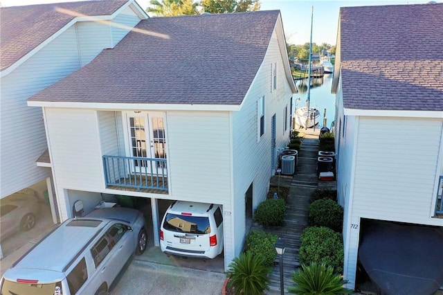 exterior space featuring a balcony, cooling unit, a carport, and a garage