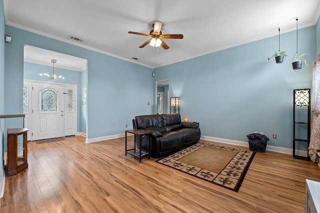 living room featuring light wood-type flooring, ceiling fan with notable chandelier, and crown molding