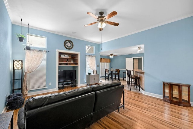 living room with light wood-type flooring, a wealth of natural light, and ornamental molding