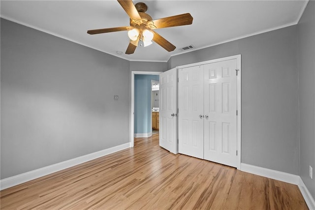 unfurnished bedroom featuring ornamental molding, a closet, light wood-type flooring, and ceiling fan