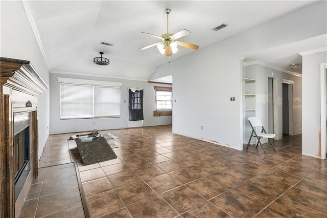 unfurnished living room with dark tile patterned flooring, vaulted ceiling, ceiling fan, and crown molding