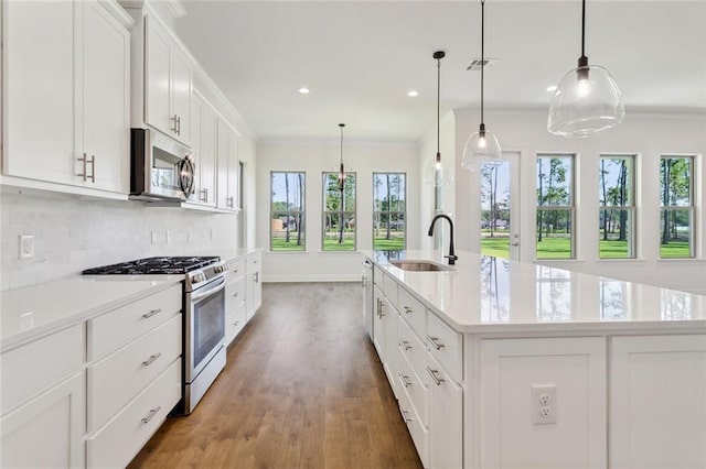 kitchen featuring pendant lighting, sink, an island with sink, white cabinetry, and stainless steel appliances