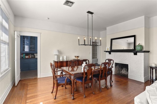 dining space with a fireplace, wood-type flooring, and a notable chandelier