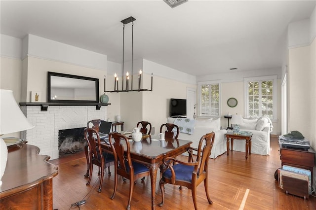 dining room with a fireplace, hardwood / wood-style flooring, and a chandelier