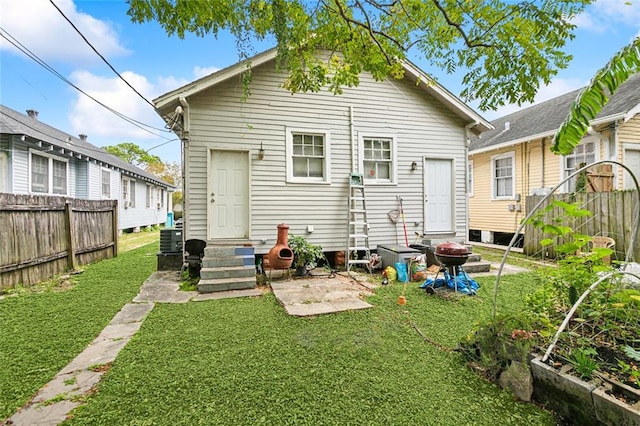 rear view of house featuring central AC unit and a lawn