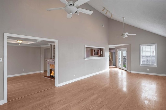 unfurnished living room with high vaulted ceiling, light hardwood / wood-style flooring, ceiling fan, track lighting, and french doors