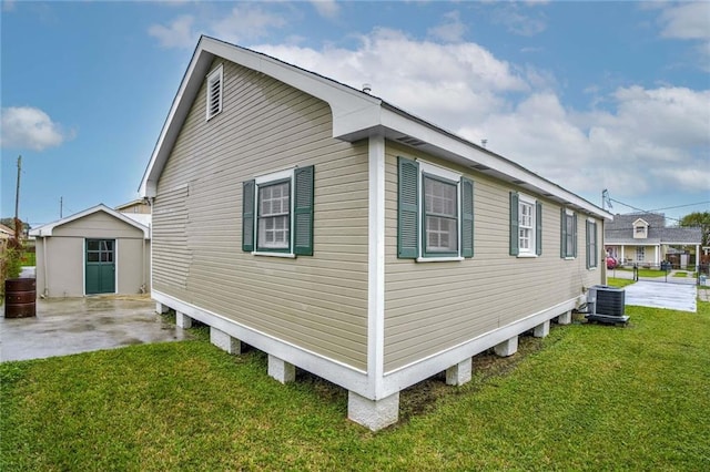 view of property exterior featuring an outbuilding, a lawn, and central air condition unit