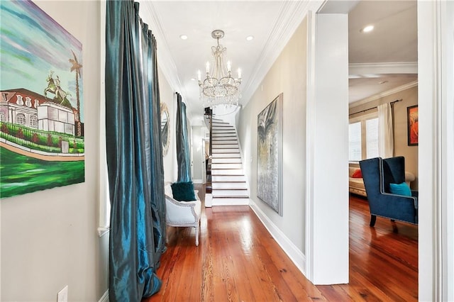 hall featuring hardwood / wood-style flooring, crown molding, and an inviting chandelier