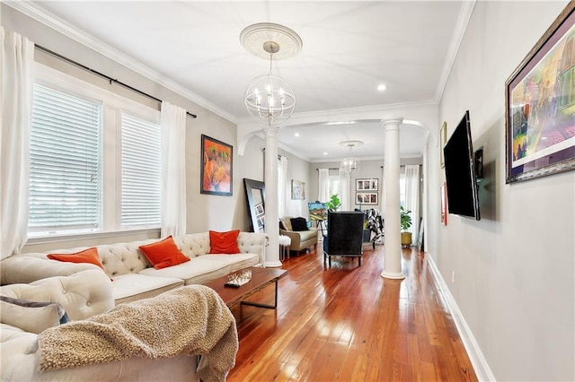 living room featuring hardwood / wood-style flooring, a chandelier, crown molding, and decorative columns