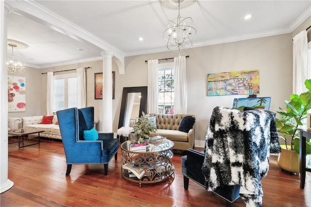 living area with decorative columns, an inviting chandelier, hardwood / wood-style flooring, and ornamental molding