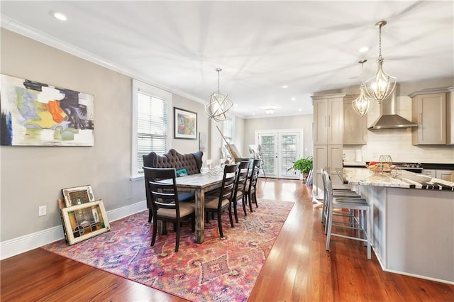 dining space featuring dark hardwood / wood-style flooring, a notable chandelier, a healthy amount of sunlight, and crown molding