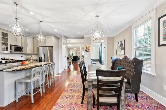 dining space featuring ornamental molding, dark wood-type flooring, and an inviting chandelier