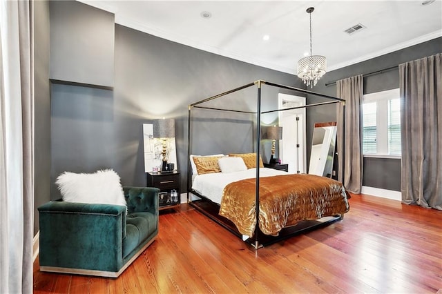 bedroom with hardwood / wood-style floors, crown molding, and an inviting chandelier