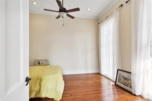 living area with hardwood / wood-style flooring, ceiling fan, and crown molding