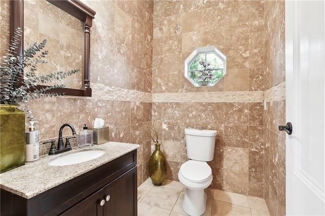 bathroom featuring tile walls, vanity, and toilet