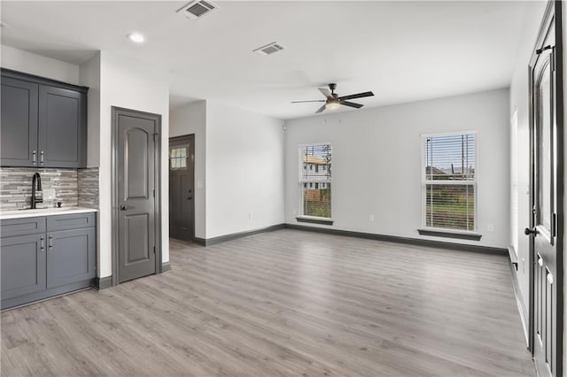 unfurnished living room featuring light wood-type flooring, sink, and ceiling fan