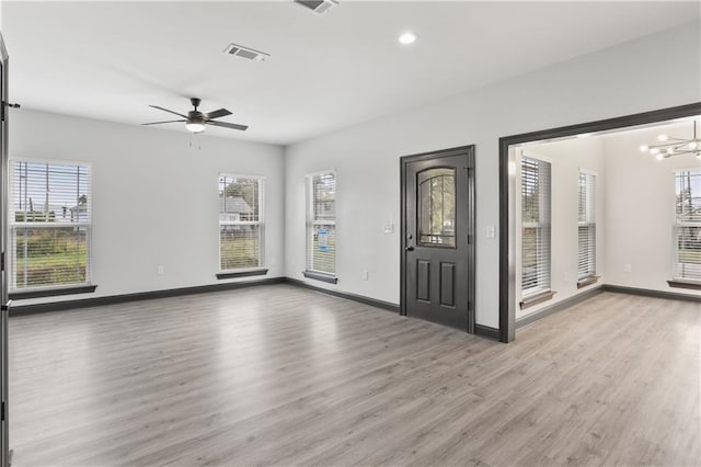 entryway featuring light hardwood / wood-style floors, ceiling fan with notable chandelier, and a healthy amount of sunlight