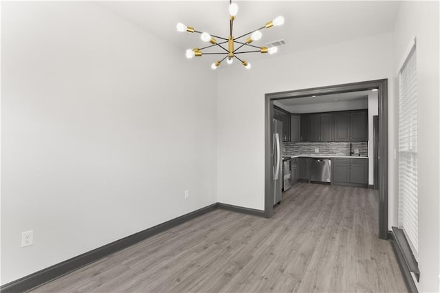 unfurnished dining area with a chandelier and light hardwood / wood-style flooring