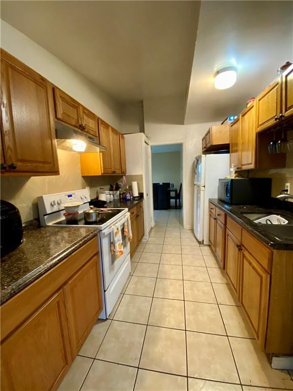 kitchen with white appliances, sink, and light tile patterned floors