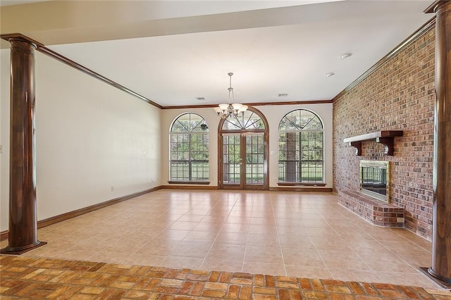 unfurnished living room with ornamental molding, a fireplace, a notable chandelier, and decorative columns