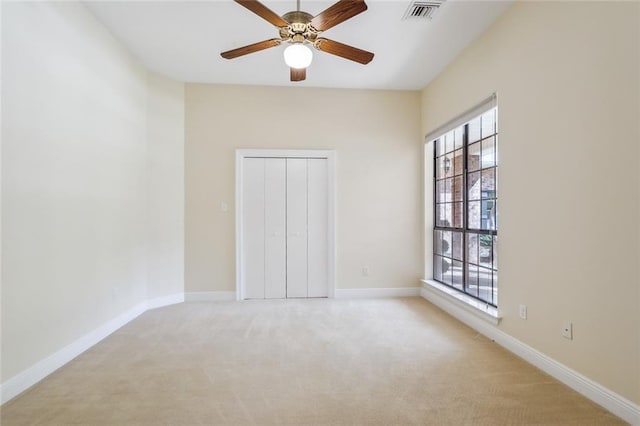 empty room featuring ceiling fan and light colored carpet