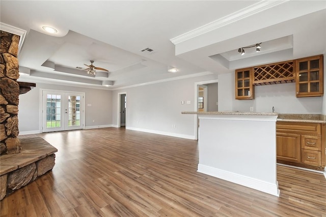 kitchen featuring light wood-type flooring, crown molding, and a tray ceiling