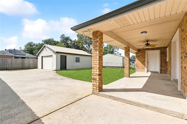 view of patio / terrace with a garage, ceiling fan, and an outbuilding