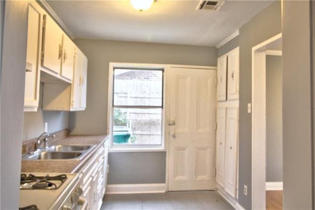 kitchen featuring white cabinetry, stainless steel range, sink, and light tile patterned floors