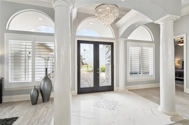 foyer entrance featuring french doors, ornamental molding, and ornate columns