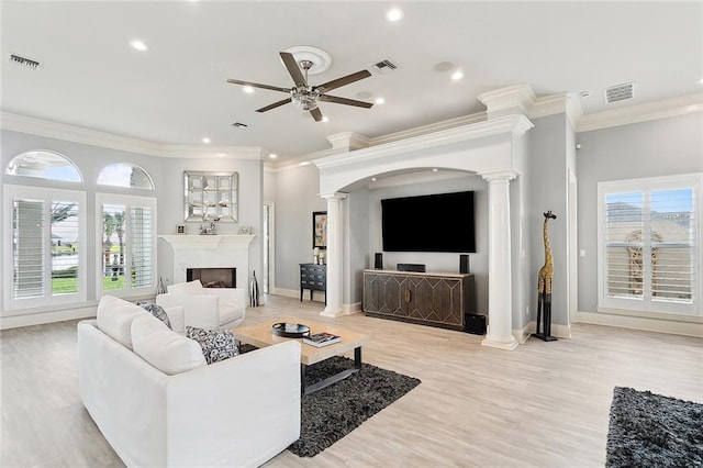 living room with crown molding, decorative columns, and a healthy amount of sunlight