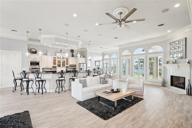 living room with a fireplace, ornamental molding, and light hardwood / wood-style floors