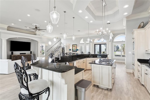 kitchen with a large island with sink, ornate columns, a kitchen breakfast bar, and decorative light fixtures