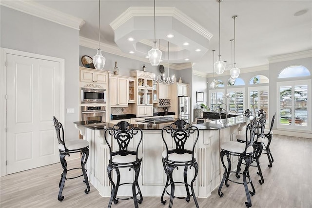 kitchen with a large island with sink, appliances with stainless steel finishes, a breakfast bar area, and pendant lighting