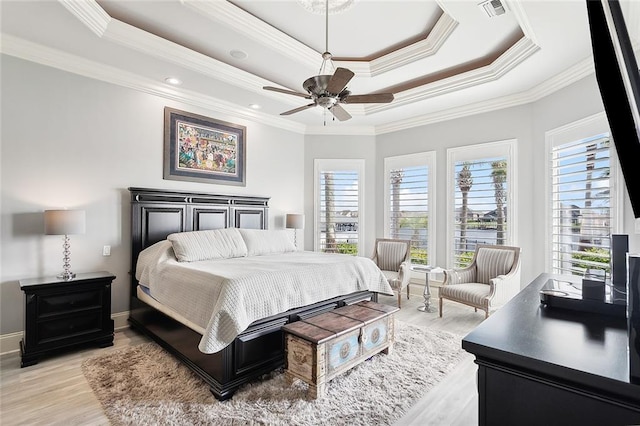 bedroom with light wood-type flooring, ornamental molding, ceiling fan, and a raised ceiling