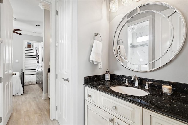 bathroom featuring ceiling fan, hardwood / wood-style flooring, crown molding, and vanity