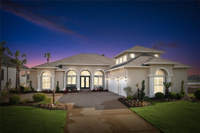 view of front of home with a yard, french doors, and a garage