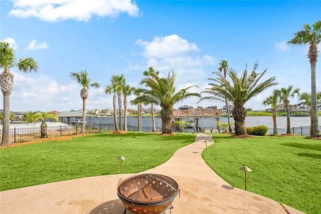 view of property's community featuring a water view, a lawn, and a fire pit