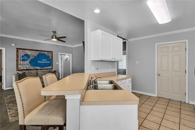 kitchen with kitchen peninsula, sink, crown molding, and a breakfast bar