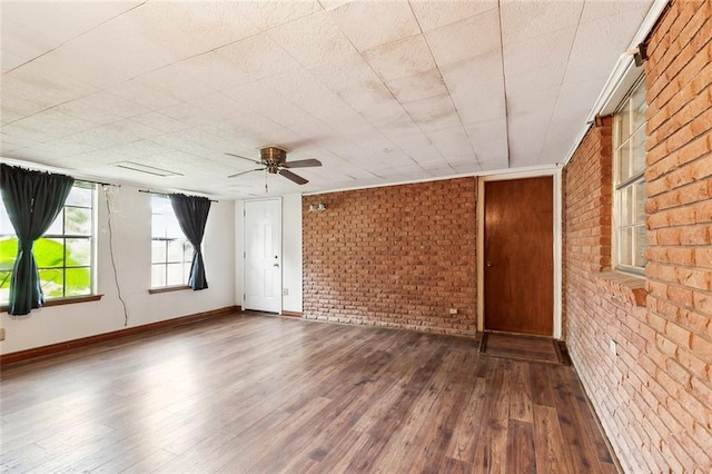 spare room with dark hardwood / wood-style floors, ceiling fan, and brick wall