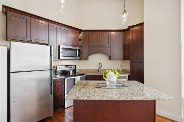 kitchen featuring pendant lighting, a kitchen island, dark wood-type flooring, and appliances with stainless steel finishes