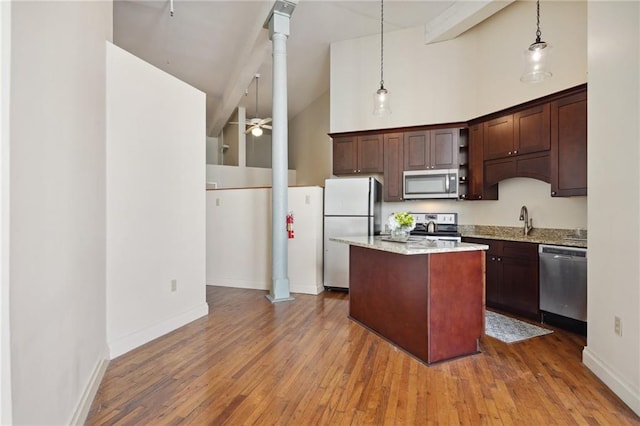 kitchen with ceiling fan, stainless steel appliances, high vaulted ceiling, decorative light fixtures, and hardwood / wood-style flooring