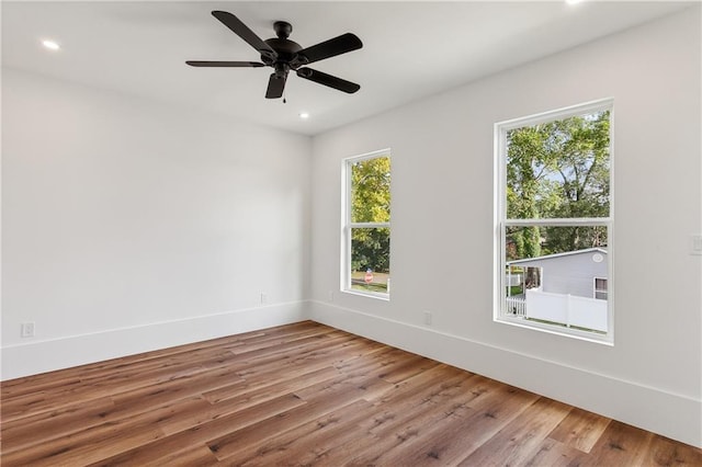 spare room with light hardwood / wood-style flooring, ceiling fan, and a healthy amount of sunlight