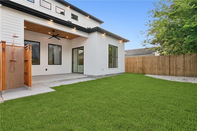 rear view of house featuring ceiling fan, a yard, and a patio