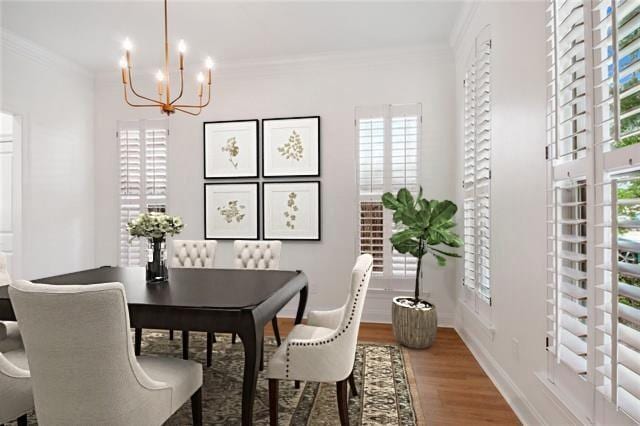 dining space with hardwood / wood-style flooring, an inviting chandelier, and crown molding