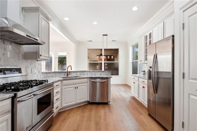 kitchen with white cabinetry, appliances with stainless steel finishes, wall chimney exhaust hood, and sink