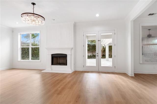 unfurnished living room with ornamental molding, a chandelier, french doors, and light hardwood / wood-style floors