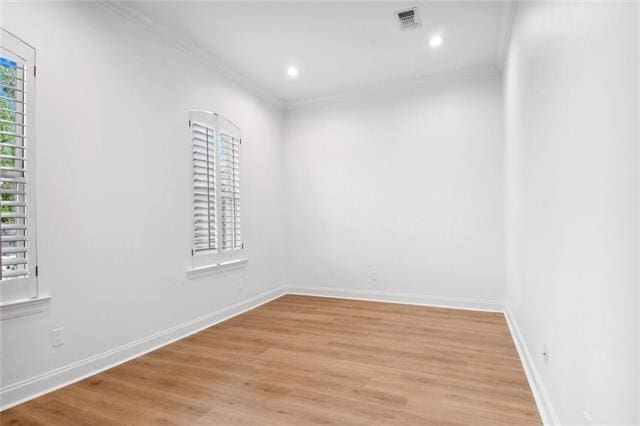 empty room with ornamental molding and light hardwood / wood-style flooring